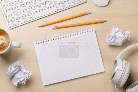 Photo for Top view of blank notepad, keyboard, headphones, coffee and crumpled papers on desk, depicting unsuccessful attempts at writing - Royalty Free Image