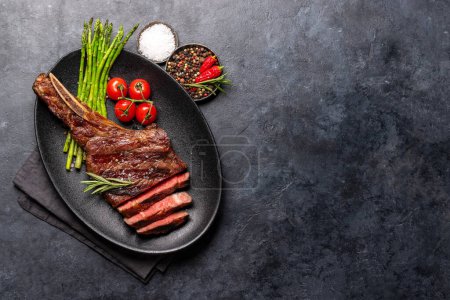 Photo for Medium rare grilled Tomahawk beef steak with asparagus. Flat lay with copy space - Royalty Free Image
