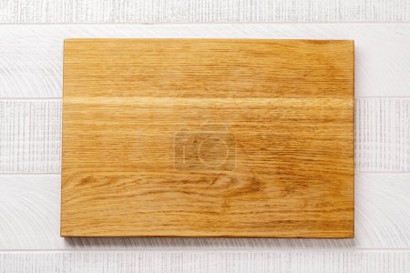 Photo for Wooden cutting board on white kitchen table. Flat lay with copy space - Royalty Free Image