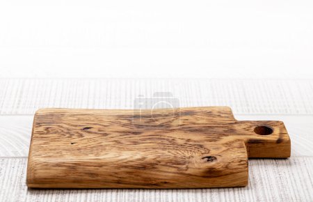Foto de Wooden cutting board on white kitchen table. With copy space - Imagen libre de derechos