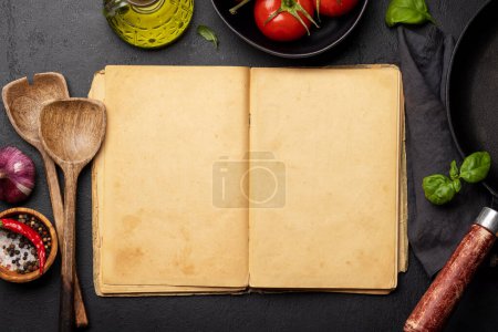 Vue du haut vers le bas d'une table de cuisine avec des ingrédients, des ustensiles et un livre de cuisine ouvert avec des pages vides, parfait pour créer une maquette pour les recettes ou les menus