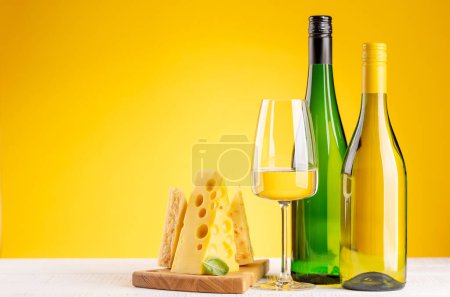 Téléchargez les photos : Various cheese on board and white wine. Over yellow background with copy space - en image libre de droit