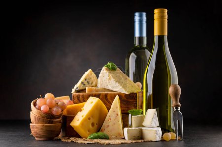 Photo for Various cheese on board and white wine. Over dark background with copy space - Royalty Free Image