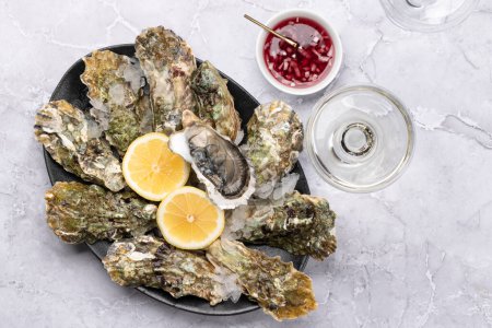 Foto de Fresh oysters with sauce and lemons. With glass of sparkling wine. Flat lay - Imagen libre de derechos