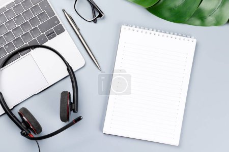 Foto de Escritorio de oficina de vista superior con computadora portátil, suministros de oficina y auriculares. Espacio de trabajo plano con luz soleada y espacio de copia - Imagen libre de derechos