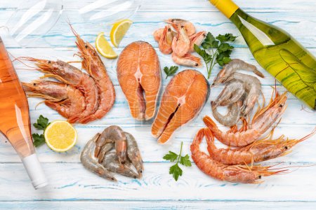 Une photo panoramique de fruits de mer frais comme les crevettes, le homard et les steaks de truite, accompagnés de vin blanc et rose