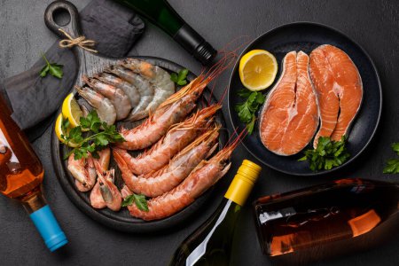Photo for A top view of fresh seafood such as shrimp, lobster, and trout steaks, accompanied by white and rose wine - Royalty Free Image