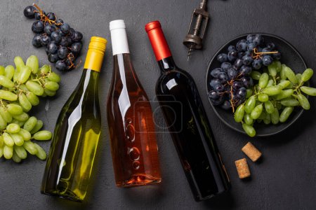 Foto de Una vista superior de botellas de vino, uvas, sacacorchos y tapones de vino en una mesa, con mucho espacio abierto para el texto. Puesta plana - Imagen libre de derechos