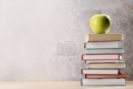 Foto de Montón de libros sobre escritorio, manzana y espacio para la creatividad - Imagen libre de derechos