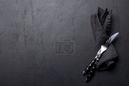 Photo for Empty dark stone table with napkin, fork and knife. Flat lay with copy space - Royalty Free Image