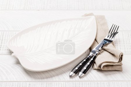 Téléchargez les photos : Plaque vide en forme de feuille avec fourchette et couteau sur table en bois blanc - en image libre de droit
