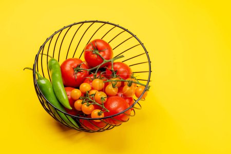 Foto de Hortalizas frescas de jardín en cesta. Tomates y pimienta. Cocina italiana. En amarillo con espacio de copia - Imagen libre de derechos