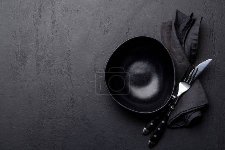 Foto de Placa vacía con tenedor y cuchillo sobre mesa de piedra oscura. Piso con espacio de copia - Imagen libre de derechos