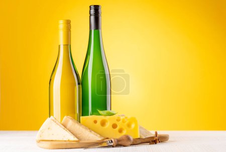 Téléchargez les photos : Various cheese on board and white wine. Over yellow background with copy space - en image libre de droit