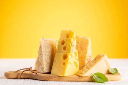 Photo for Various cheese on board. Over yellow background with copy space - Royalty Free Image