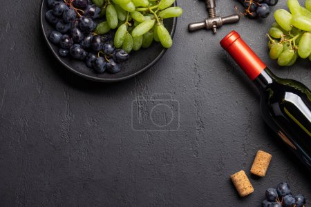 Photo for A top view of a wine bottle, grapes, corkscrew, and wine corks on a table, with plenty of open space for text. Flat lay - Royalty Free Image