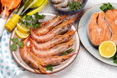 Photo for A top view of fresh seafood such as shrimp, langoustines, and trout steaks, accompanied by white and rose wine - Royalty Free Image