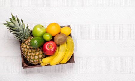 Téléchargez les photos : Boîte en bois pleine d'aliments sains aux fruits. Pose plate avec espace de copie - en image libre de droit