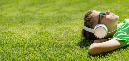 Foto de Un chico relajándose en la hierba, escuchando música con auriculares - Imagen libre de derechos