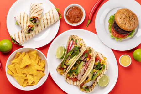 Photo for Mexican food featuring tacos, burritos, burgers and more. Flat lay over red - Royalty Free Image