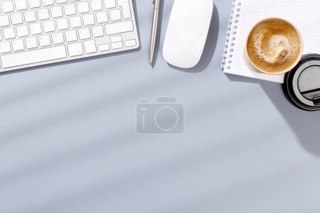 Foto de Escritorio de oficina de vista superior con teclado, suministros de oficina y café. Espacio de trabajo plano con luz soleada y espacio de copia - Imagen libre de derechos