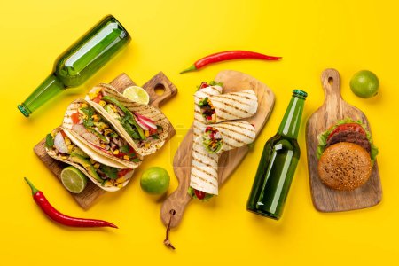 Foto de Comida mexicana con tacos, burritos, hamburguesas y más. Piso acostado sobre amarillo - Imagen libre de derechos