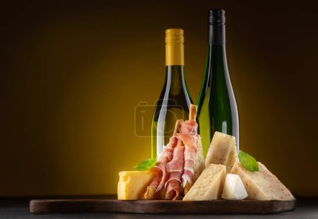 Photo for Antipasto board with various cheese and wine bottles - Royalty Free Image