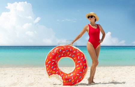 Photo for Beautiful young woman with inflatable donut ring relaxing on sea beach. Summer vacation. With copy space - Royalty Free Image