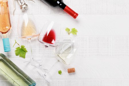 Foto de Copas y botellas de vino blanco, rosa y tinto. Piso con espacio de copia - Imagen libre de derechos