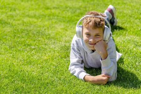 Photo for A boy relaxing on grass, listening to music with headphones - Royalty Free Image