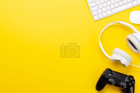 Foto de Equipo de juego y accesorios tecnológicos sobre un fondo amarillo, perfecto para juegos y temas relacionados con la tecnología. Piso con espacio de copia - Imagen libre de derechos