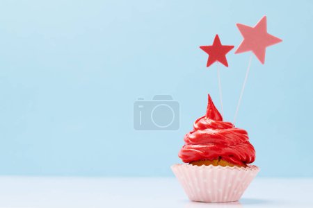 Photo for Red cream cupcake with decor on blue background with copy space - Royalty Free Image