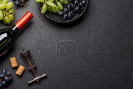 Foto de Una vista superior de una botella de vino, uvas, sacacorchos y tapones de vino en una mesa, con mucho espacio abierto para el texto - Imagen libre de derechos