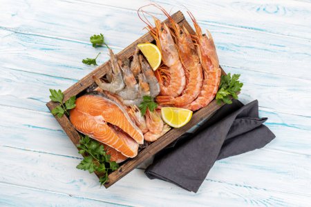 Téléchargez les photos : Une vue de dessus des fruits de mer frais tels que les crevettes, langoustines, et steaks de truite dans la boîte en bois. Pose plate - en image libre de droit