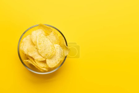Foto de Cuenco de papas fritas sobre un fondo amarillo con espacio para copiar. Puesta plana - Imagen libre de derechos