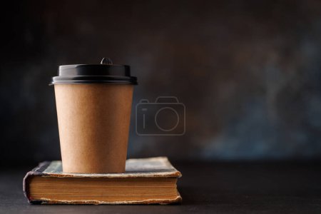 Photo for Aromatic coffee in a paper cup over an old book. With copy space - Royalty Free Image