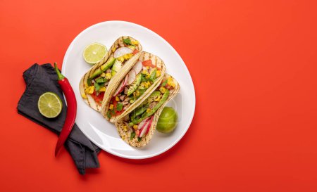 Photo for Mexican food featuring tacos with meat and grilled vegetables. Flat lay over red with copy space - Royalty Free Image