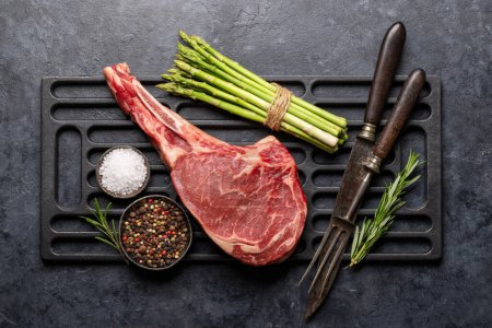 Photo for Raw Tomahawk beef steak, asparagus and spices. Ready for grilling. Flat lay - Royalty Free Image
