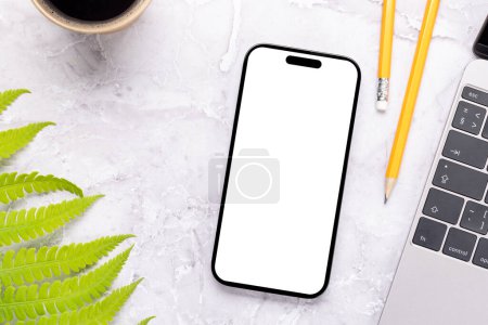 Photo for Smartphone with blank screen on a table surrounded by green nature leaves, perfect design mockup - Royalty Free Image