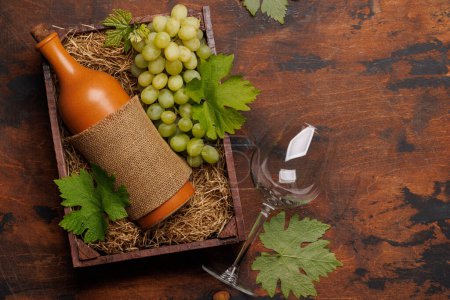 Une bouteille de vin rouge et des raisins frais, présentés dans une boîte en bois rustique. Pose plate avec espace de copie