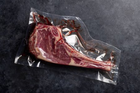 Téléchargez les photos : Raw Tomahawk beef steak vacuum packed. Ready for grilling. Flat lay - en image libre de droit