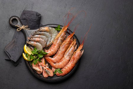 Téléchargez les photos : Une vue de dessus des fruits de mer frais tels que les langoustines. Pose plate sur table en pierre sombre avec espace de copie - en image libre de droit
