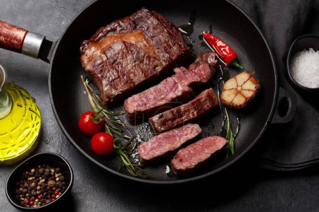 Téléchargez les photos : Steak de bœuf de côtelette grillé dans une poêle avec des herbes et des épices - en image libre de droit