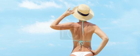 Photo for Back of beautiful girl in bikini on the sea beach in front of sunny sky. Enjoy and relax in summer with copy space - Royalty Free Image