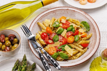 Foto de Un delicioso plato de pasta italiana adornada con tomates frescos y hojas aromáticas de albahaca, espárragos a la parrilla y gambas - Imagen libre de derechos