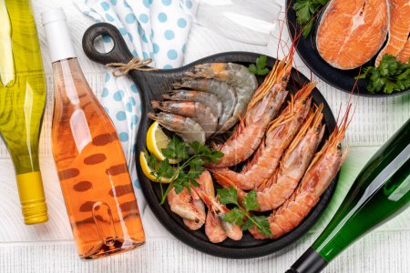 Téléchargez les photos : Fruits de mer frais comme les crevettes, le homard et les steaks de truite, accompagnés de vin blanc et rose - en image libre de droit