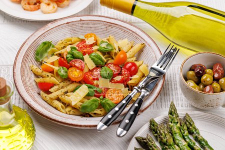 Téléchargez les photos : Assiette délicieuse de pâtes italiennes ornée de tomates fraîches et de feuilles de basilic aromatiques, d'asperges grillées et de crevettes - en image libre de droit