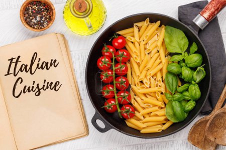 Téléchargez les photos : Une représentation vibrante du drapeau italien fait avec des pâtes, du basilic et des tomates, magnifiquement présenté dans une poêle et un livre de cuisine. Pose plate avec espace de copie - en image libre de droit