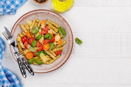 Téléchargez les photos : Assiette délicieuse de pâtes italiennes ornée de tomates fraîches et de feuilles de basilic aromatiques. Pose plate avec espace de copie - en image libre de droit