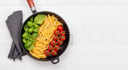 Photo for A vibrant representation of the Italian flag made with pasta, basil, and tomatoes, beautifully presented in a frying pan. Flat lay with copy space - Royalty Free Image